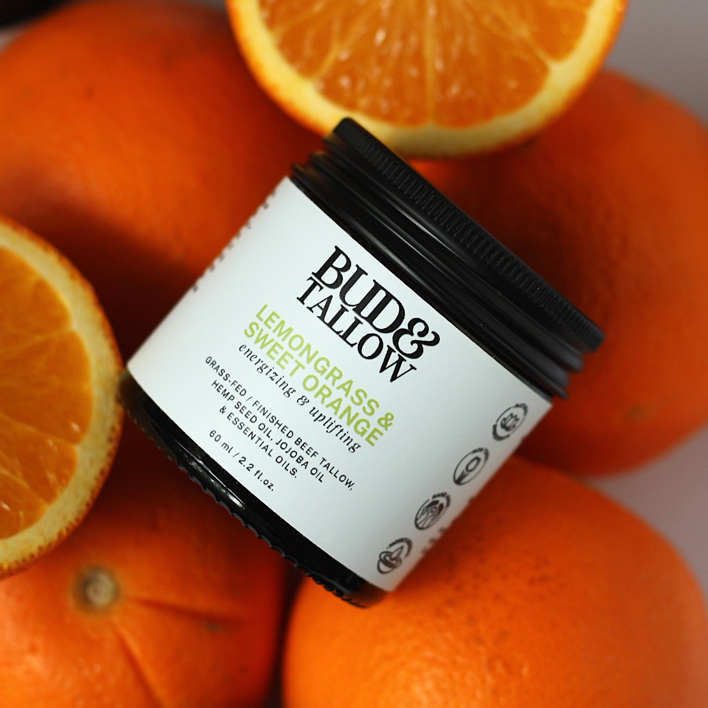 Jar of Bud & Tallow product sitting on oranges