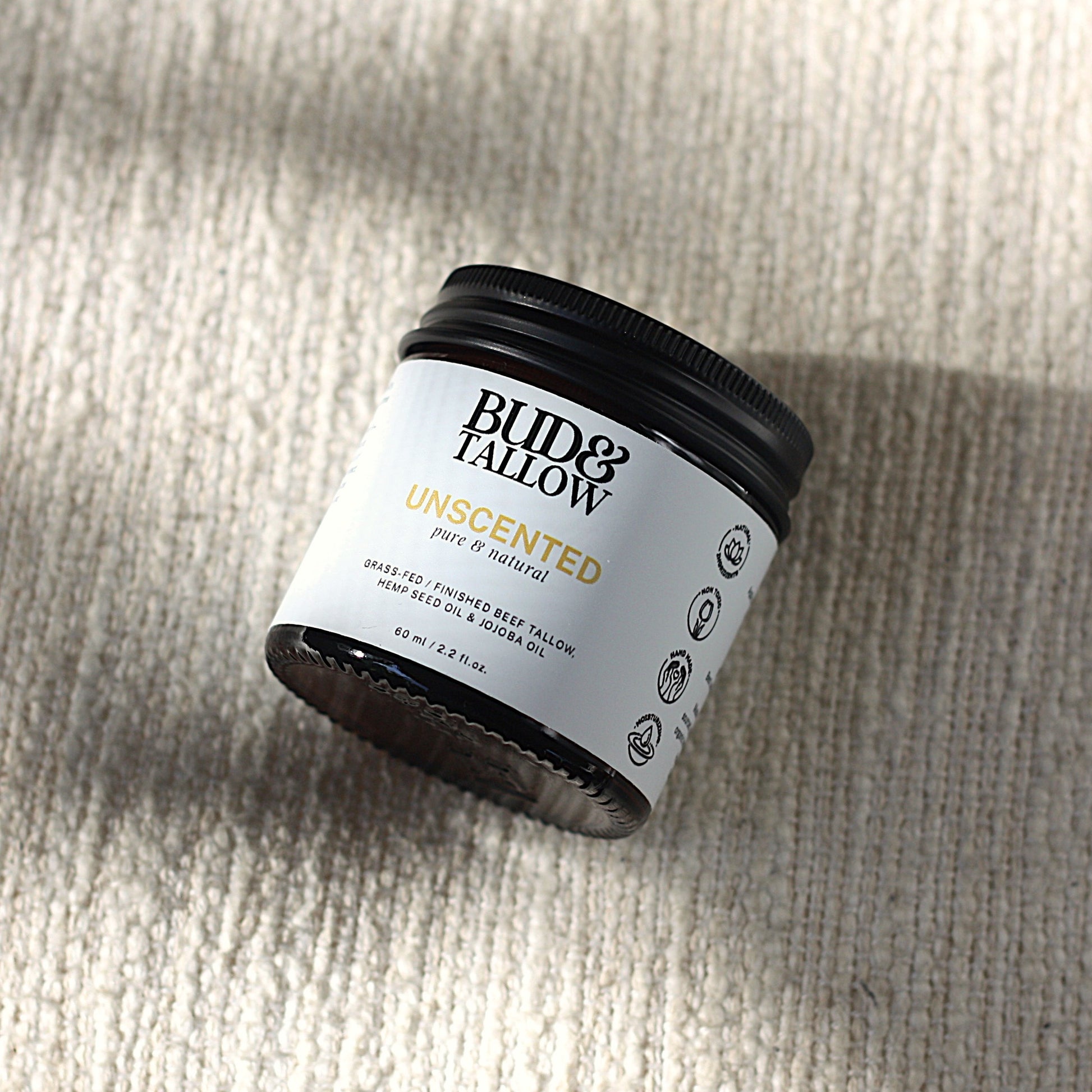 Jar of Bud & Tallow balm product on cushion