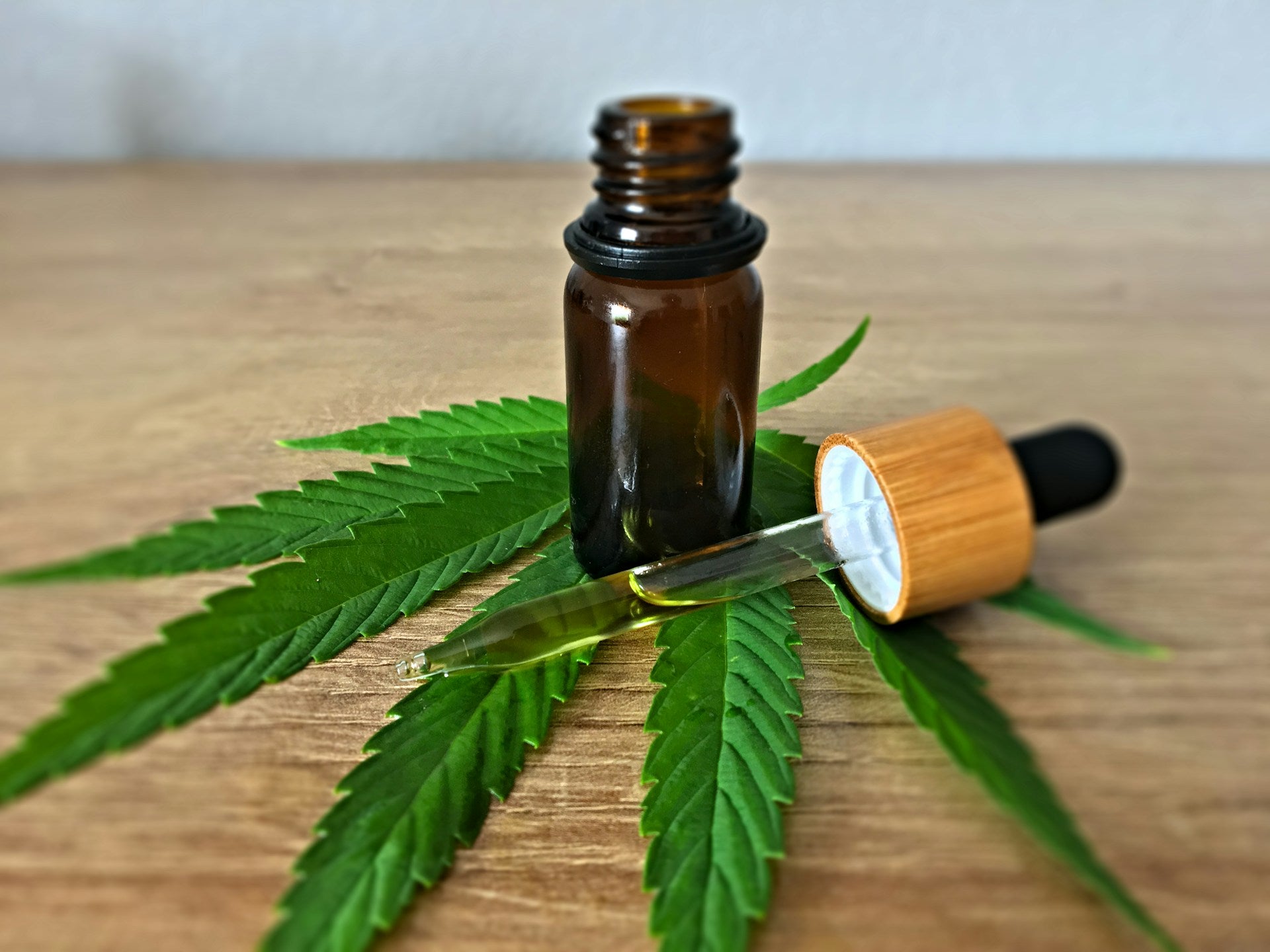 Hemp oil dropper bottle with cannabis leaf on a wooden surface